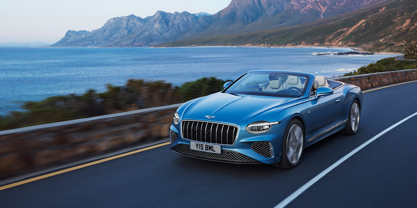 Bentley Basel New Bentley Continental GTC Azure convertible in Light Windsor blue paint with 22 inch Azure wheels and chrome grill, driving dynamically by the sea