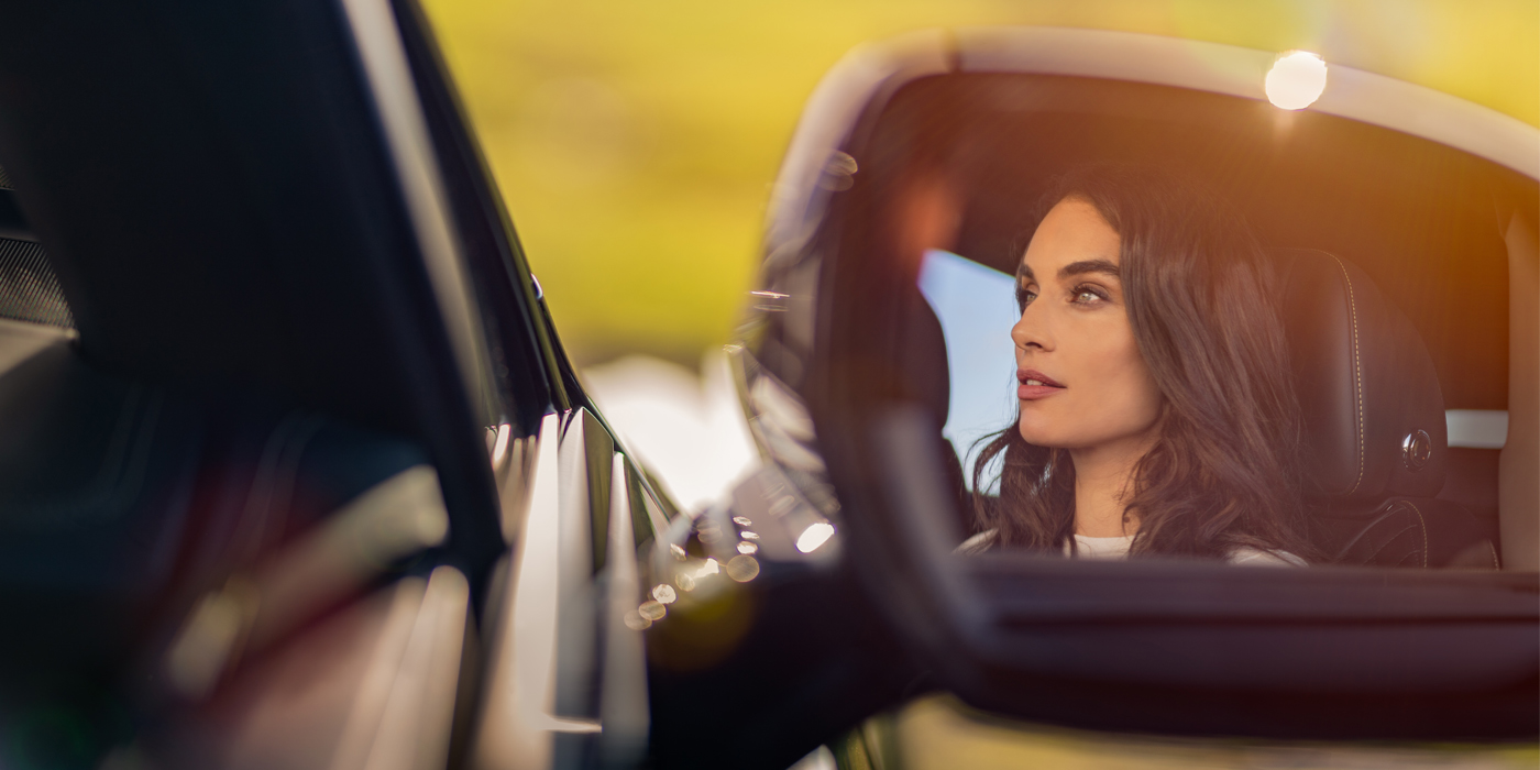 Bentley Basel profile of dark haired woman's face in mirror of Bentley car in sunlight