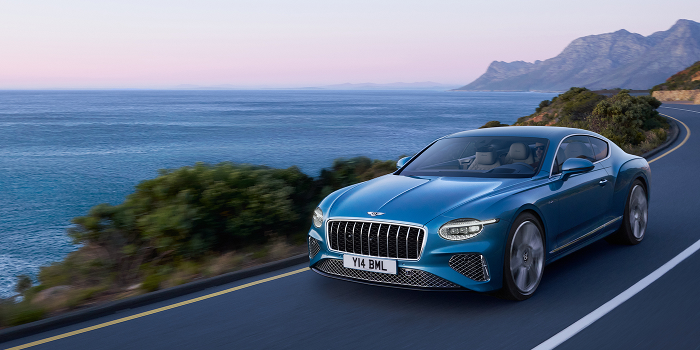 Bentley Basel New Bentley Continental GT Azure coupe in Light Windsor blue paint with 22 inch Azure wheels and chrome grill, driving dynamically by the sea