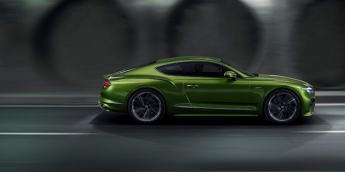  Bentley Basel Bentley Continental GT coupe in Tourmaline Green paint driving in profile on a dark road