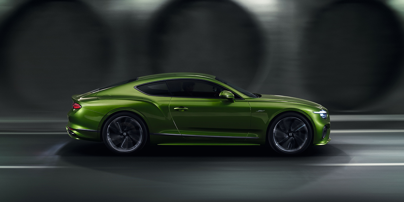 Bentley Basel Bentley Continental GT coupe in Tourmaline Green paint driving in profile on a dark road