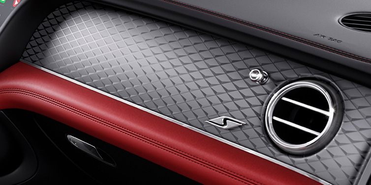 Bentley Basel Bentley Bentayga S SUV front interior dash withDark Tint Diamond Brushed Aluminium veneer and S badge surrounded by Hotspur red and Beluga black hide