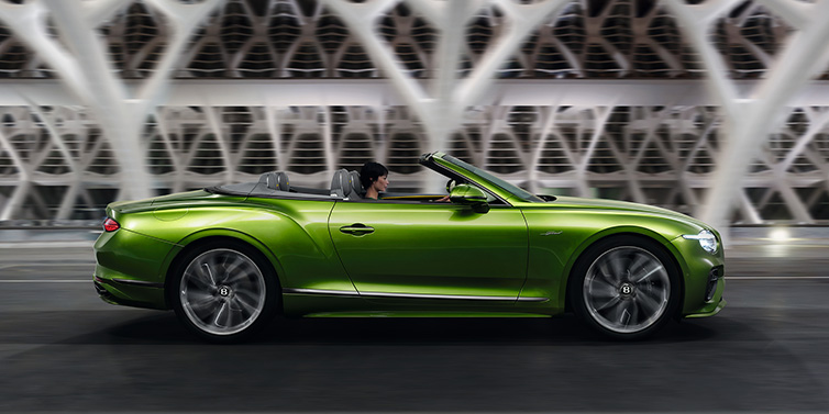 Bentley Basel Bentley Continental GTC Speed convertible side profile in Tourmaline Green paint driving dynamically on a bridge at night