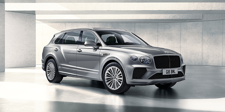 Bentley Basel Bentley Bentayga Extended Wheelbase SUV front three quarter in Moonbeam paint with a grey background