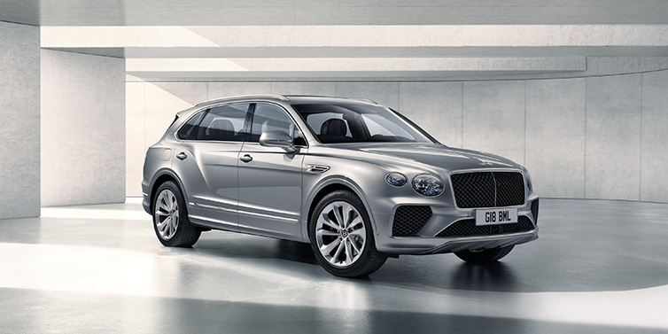 Bentley Basel Bentley Bentayga Extended Wheelbase SUV front three quarter in Moonbeam paint with a grey background