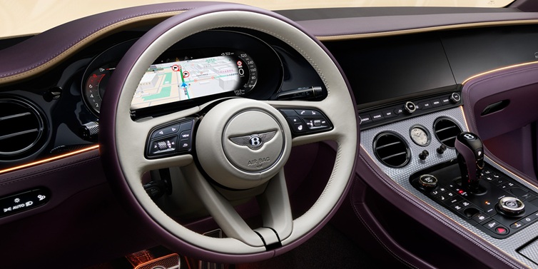 Bentley Basel Bentley Continental GT Mulliner coupe front interior showing steering wheel and drivers screens surrounded by Linen and Damson hides and Grand Black veneer